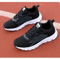 Low-top black and white running sneaker with cross strap and round toe on MD sole.