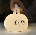White marshmallow bunny LED night light with shy face or happy face option on a table.