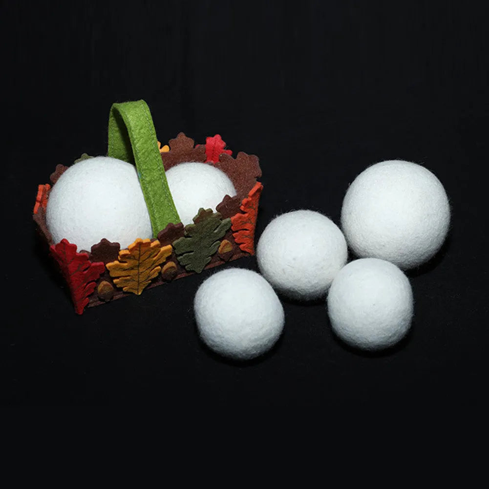 Set of 100% wool felt laundry drying balls in various sizes next to a plain cotton storage bag.