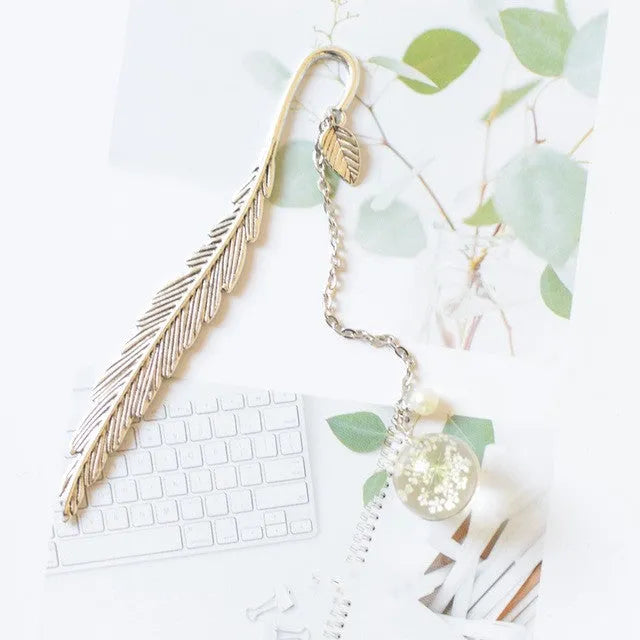 Flat metal bookmark with a dried flower inside, showing colour options like blue starry sky and dandelion.