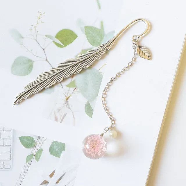 Flat metal bookmark with a dried flower inside, showing colour options like blue starry sky and dandelion.