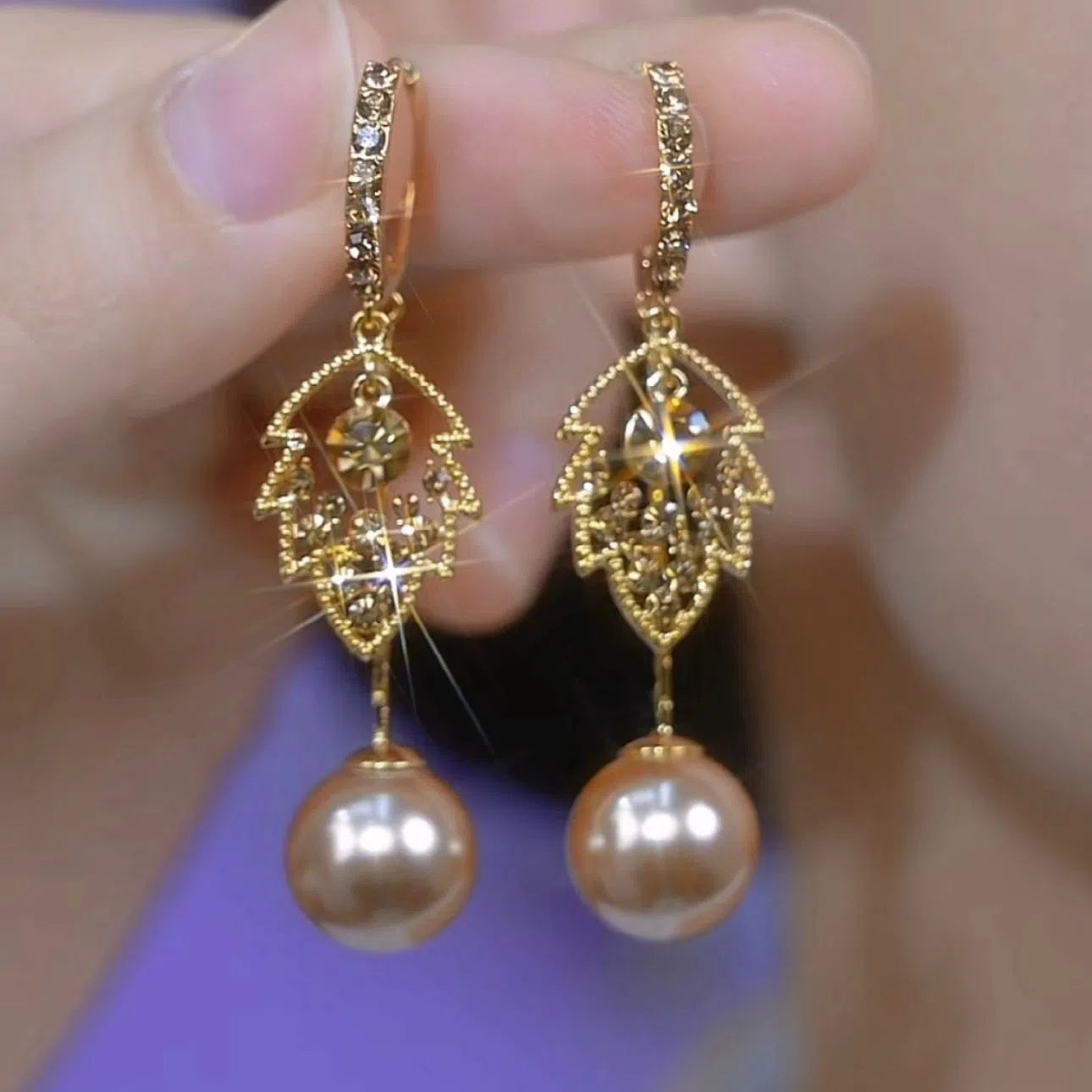 Coffee-coloured metal leaf earrings with full diamond-cut surface and pearl accents, old money style, side view on white background