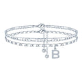 Silver-coloured copper anklet with double-circle beads and a personalised letter charm on an ankle.