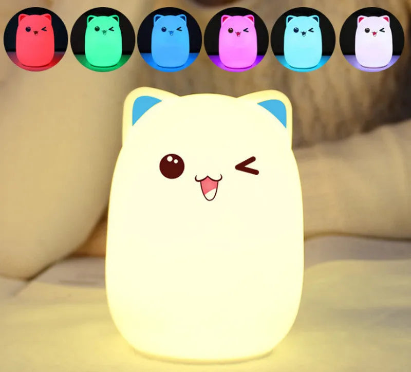 Cartoon silicone clapping night lamp in pink with USB charging cable on a bedside table