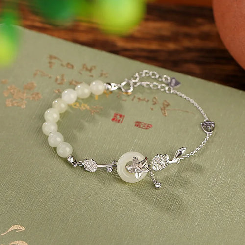 Antique style women's bracelet with peace buckle, inlaid Hetian jade lotus, on a silver chain.