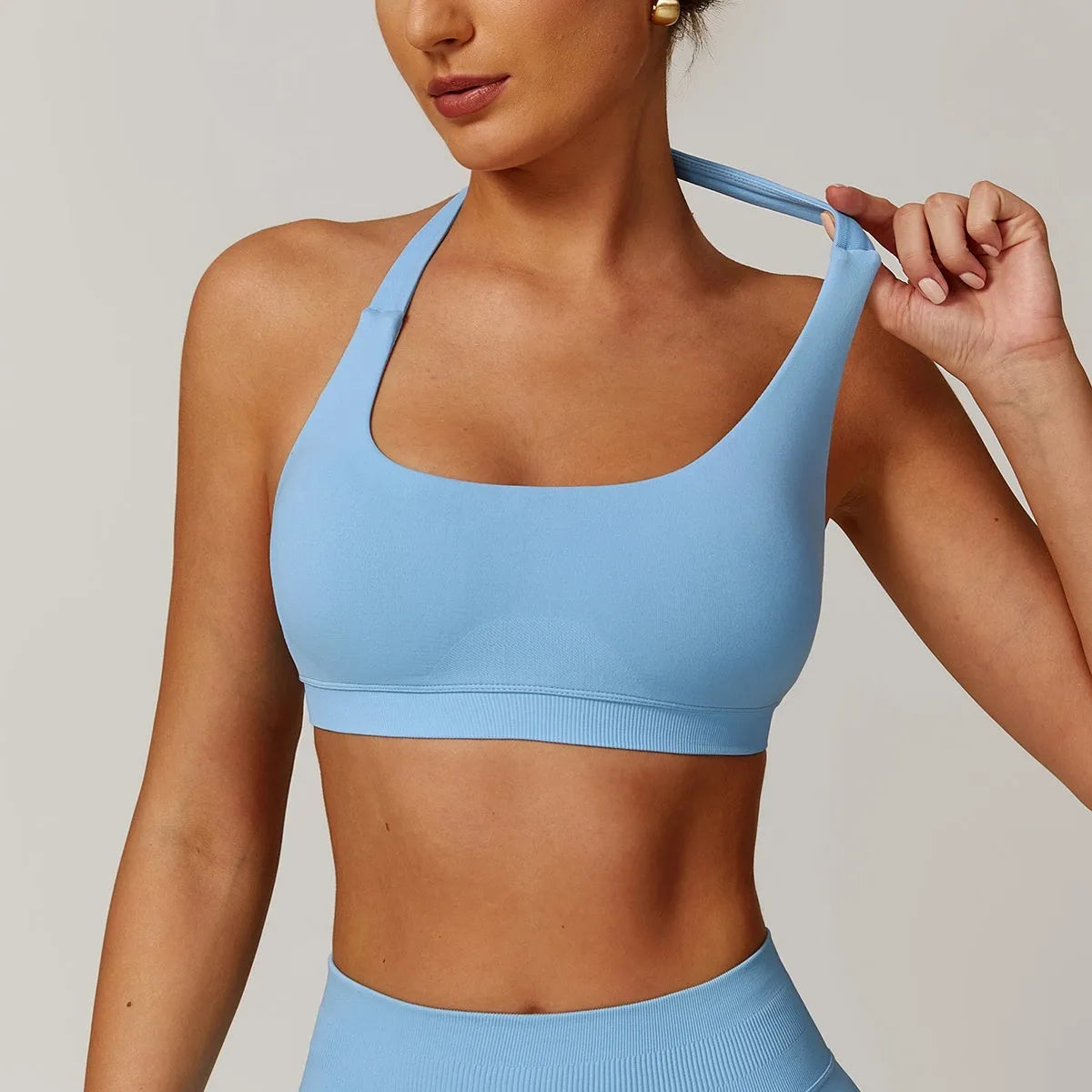 Women's black halter-neck sports bra with removable padding on a grey background.