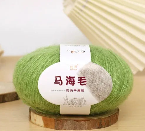 A ball of mohair yarn in a selected colour next to a hand-woven scarf example, showcasing the DIY kit.