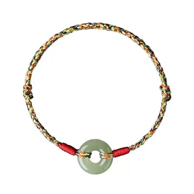 Close-up of a colourful woven rope bracelet with a silver peace buckle clasp on a wrist.