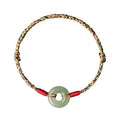Close-up of a colourful woven rope bracelet with a silver peace buckle clasp on a wrist.