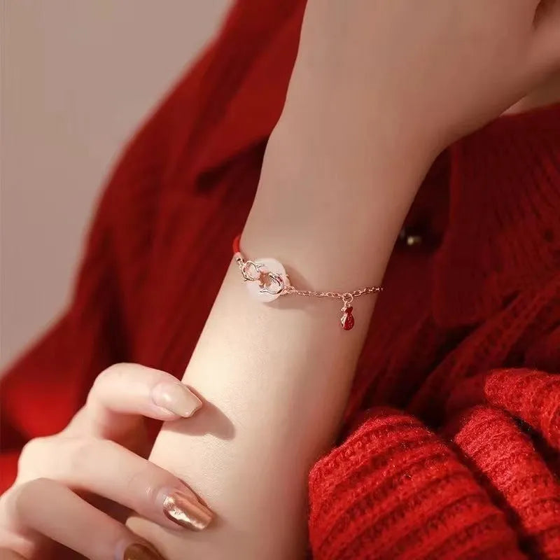 Close-up of a red rope festive koi bracelet for women with a peace buckle and fish tail details.