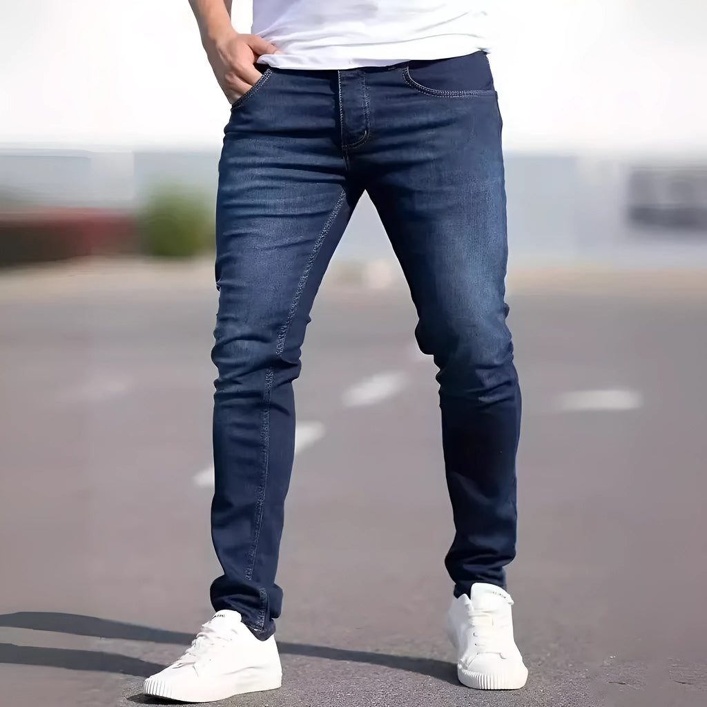 Man wearing dark blue slim fit skinny jeans with a mid-rise waist and zipper fly.