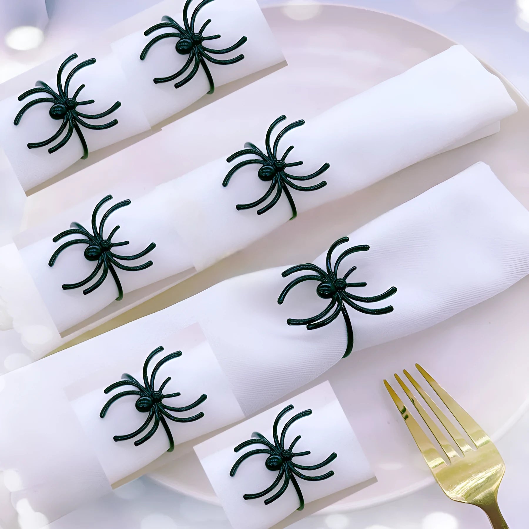 Set of six black alloy spider-shaped napkin rings for Halloween table decoration.
