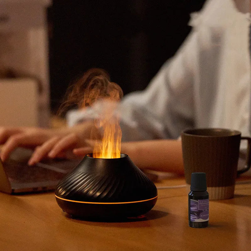 Beige volcanic flame aroma diffuser with LED light on a wooden table next to an essential oil bottle