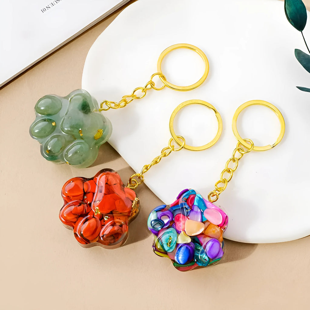 Small cat's paw shaped keychain pendant made from a natural pink crystal on a metal ring.