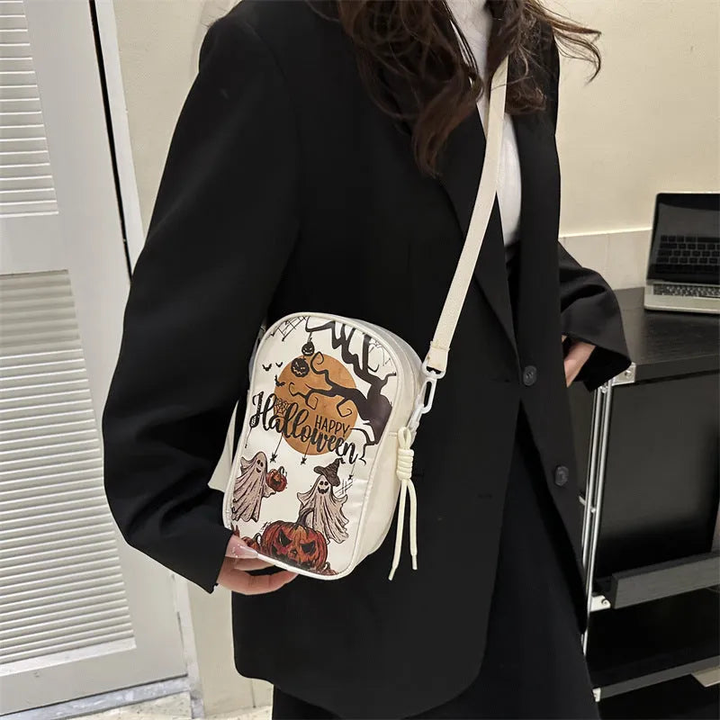 Black mini square crossbody bag with orange pumpkin, white ghost, and black bat graffiti print on the front.