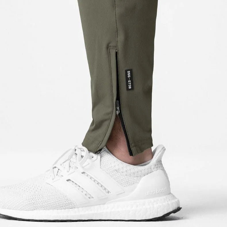 Man wearing dark grey loose-fit fitness trousers with tied ankle cuffs, suitable for gym training.