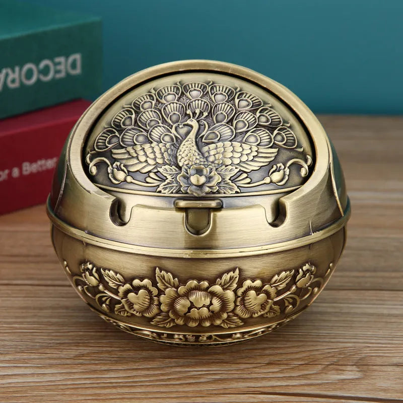 Alloy decorative ashtray in bronze with ornate peacock motif and cigarette extinguishing slot.