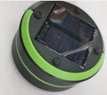 SolarBoom collapsible lantern in green with solar panel, collapsed for storage, on a wooden surface