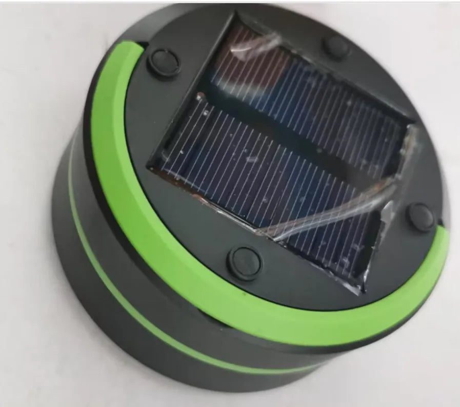 SolarBoom collapsible lantern in green with solar panel, collapsed for storage, on a wooden surface