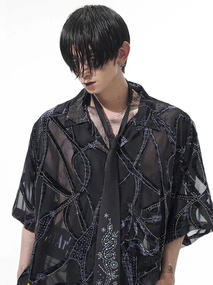 Man wearing a loose-fit black short-sleeved shirt with a translucent snake pattern print and lapel collar.