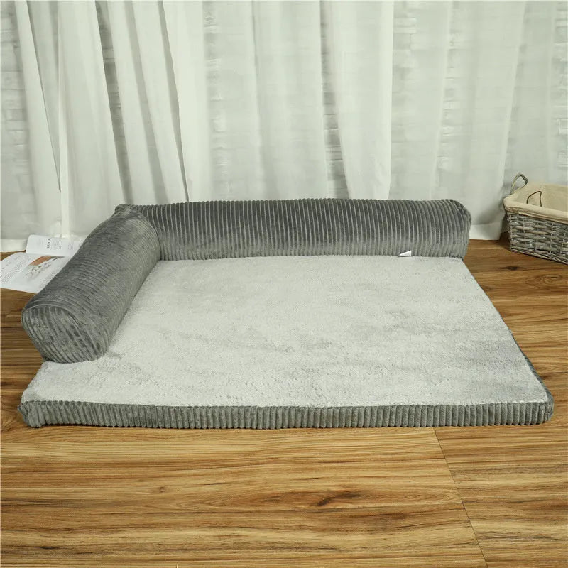 Grey corduroy pet sofa dog bed with bilateral bolsters and a non-slip cloth base on a wooden floor.