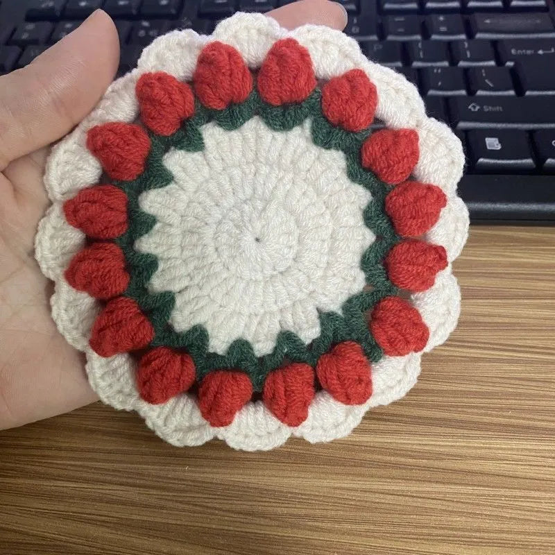 Handmade woven floral coaster in cotton and linen on a wooden table