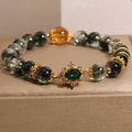 Gold electroplated women's bracelet with a green phantom quartz stone, ruby accents, rhinestones, and pearls.