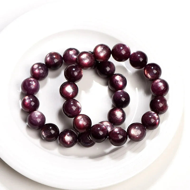Natural purple lepidolite crystal round bead bracelet with adjustable cord on a wooden surface.
