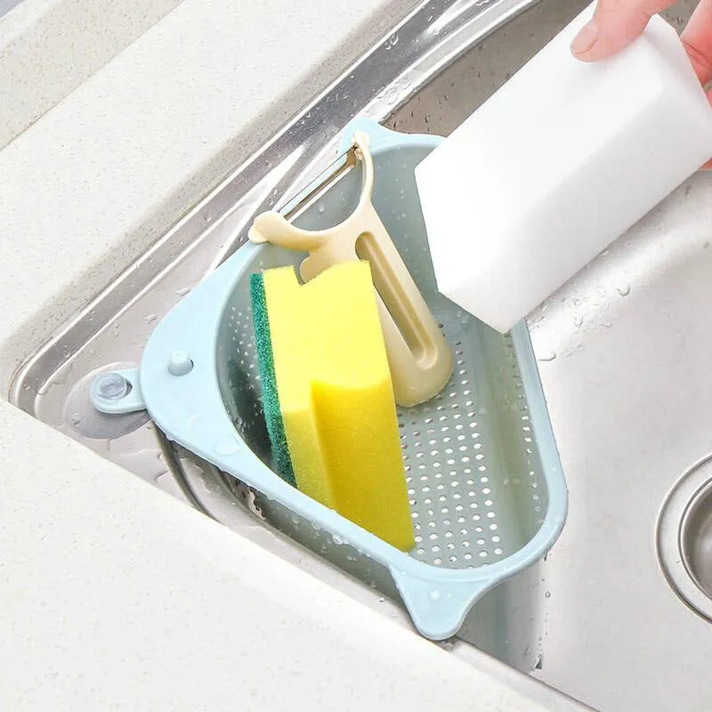 Beige plastic triangle kitchen sink rack holding a sponge and soap, hanging from a faucet.