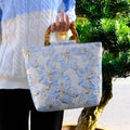 Light blue women's canvas bag with bronzing flower decoration and gold trim, showing 30cm square shape
