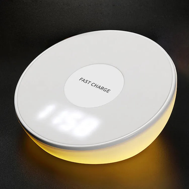 White wireless charging pad with digital clock display and night light, shown on a wooden surface.