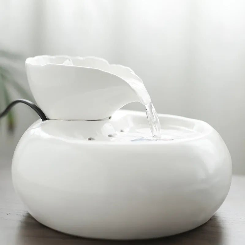 White ceramic automatic cat water dispenser with leaf design and US plug on a wooden floor