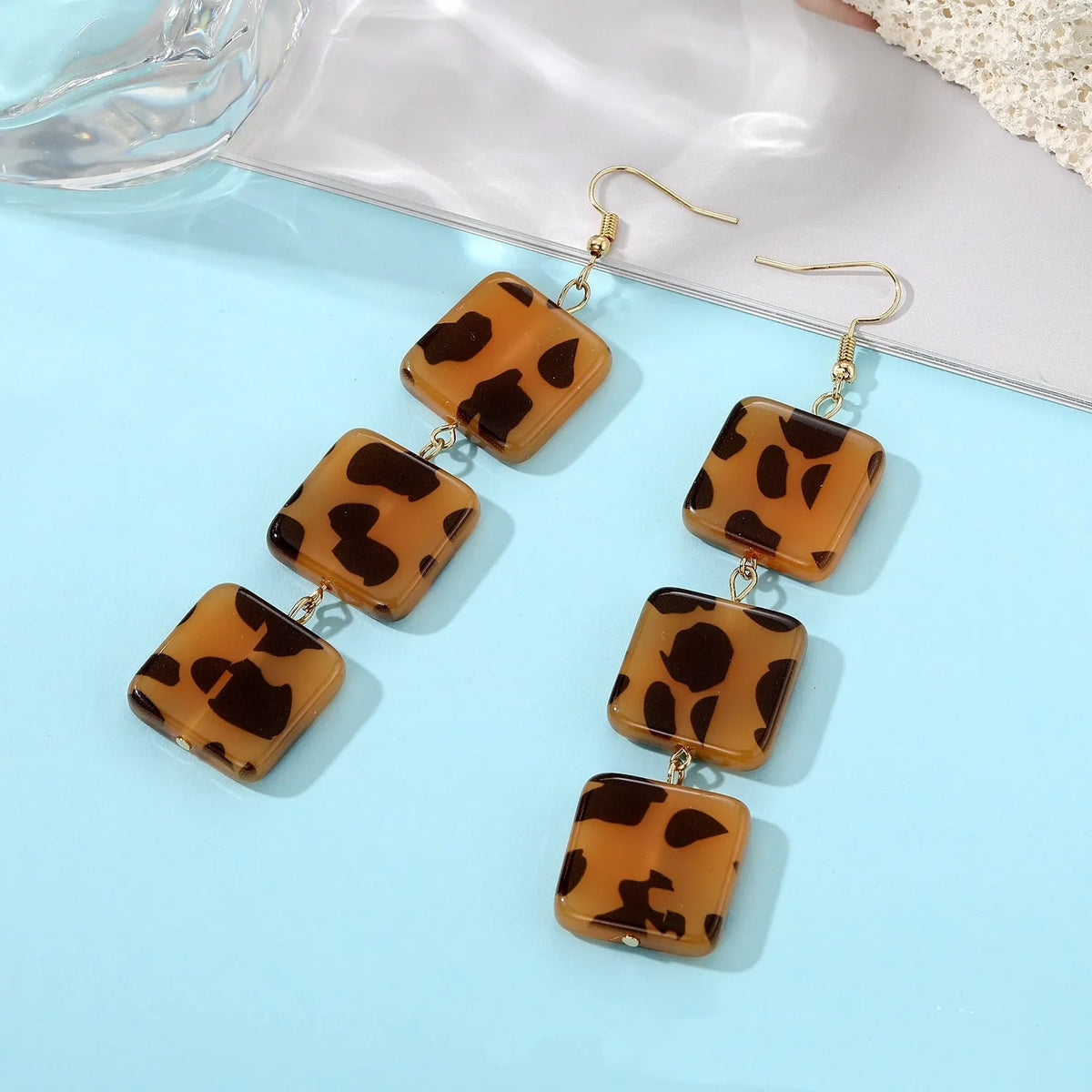 Set of three women's geometric square ear studs with leopard print, sunflower, and coloured glaze bead designs on plastic resin material