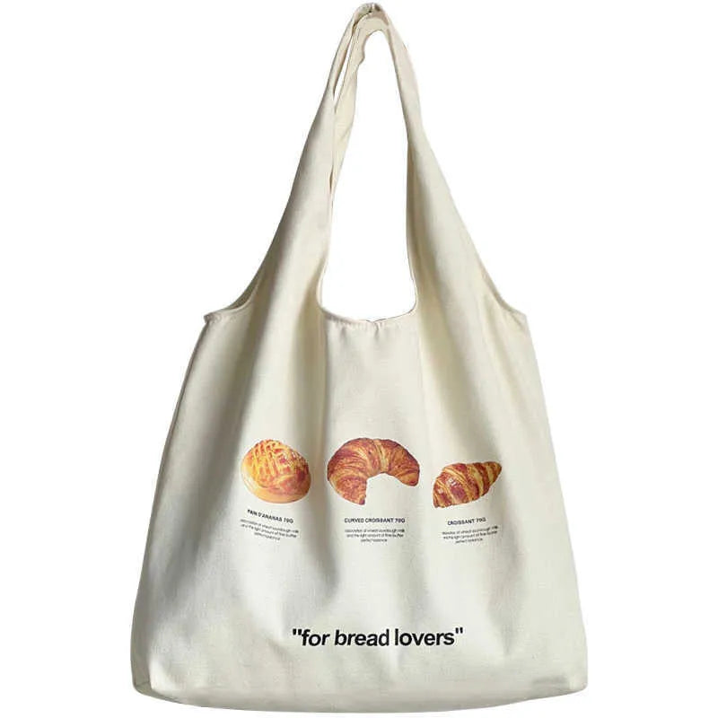 Beige canvas shoulder bag with croissant and bread print showing front panel design and shoulder strap