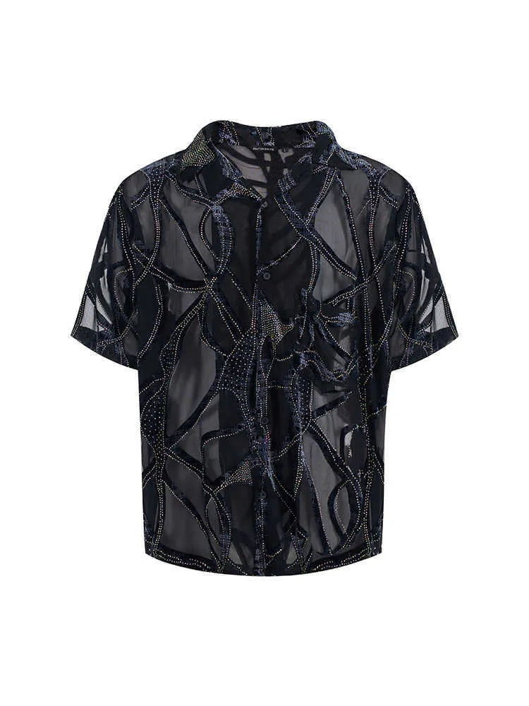 Man wearing a loose-fit black short-sleeved shirt with a translucent snake pattern print and lapel collar.