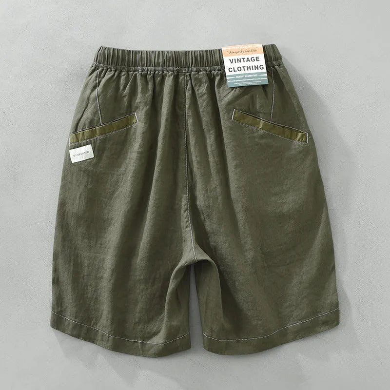 Men's loose fit linen shorts in green, showing straight drooping leg and drawstring waist.