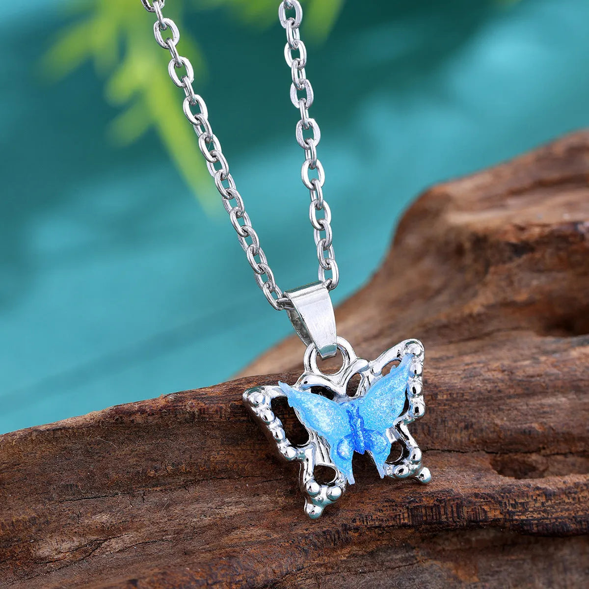 Blue three-dimensional butterfly pendant necklace for women on a light background