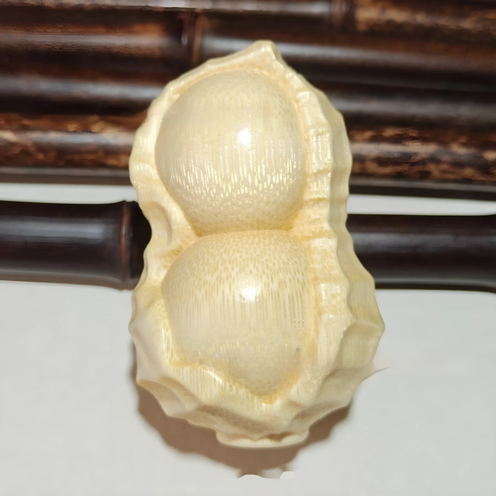Solid natural bamboo peanut ornament with engraved message on wooden surface