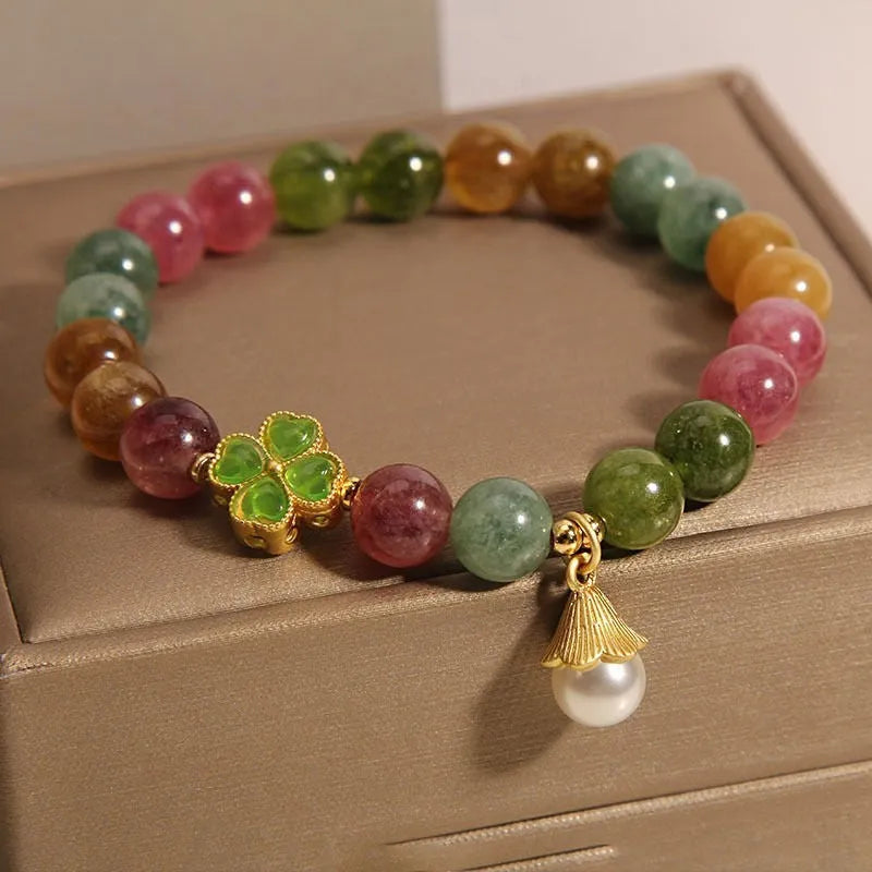 Natural colour tourmaline bracelet with four-leaf clover charm and pearl pendant on wrist