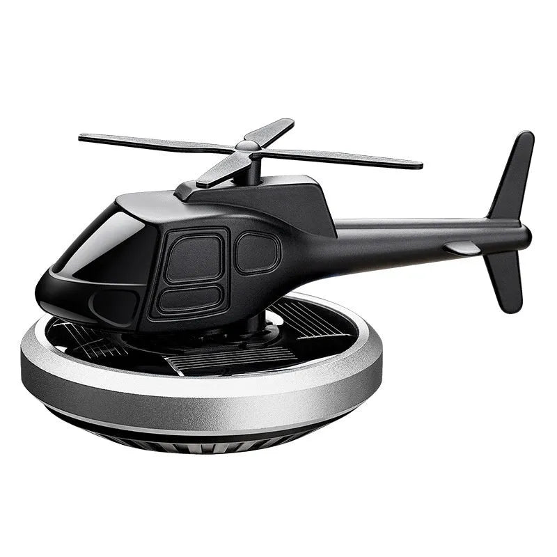 Silver metal solar helicopter car perfume ornament with rotating blades on a dashboard.