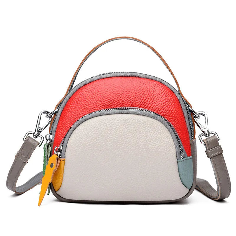 Round hand-held crossbody bag made from first layer cowhide leather with visible sewing line detail on exterior