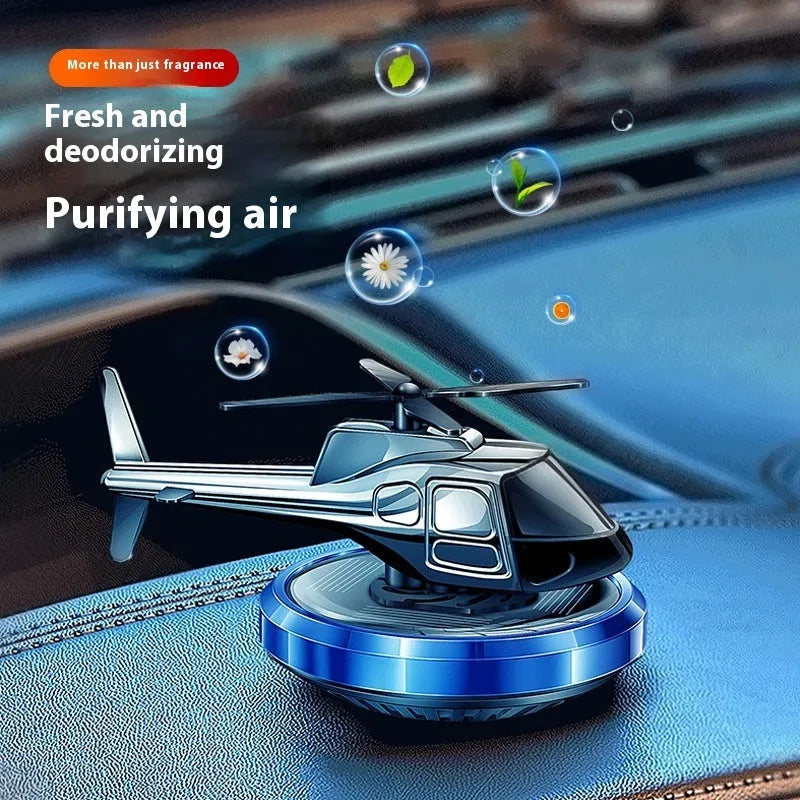 Silver metal solar helicopter car perfume ornament with rotating blades on a dashboard.