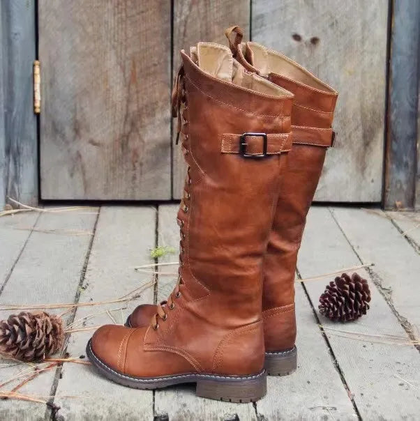 Black chunky heel high leg boots with a round toe and low heel on a plain background.