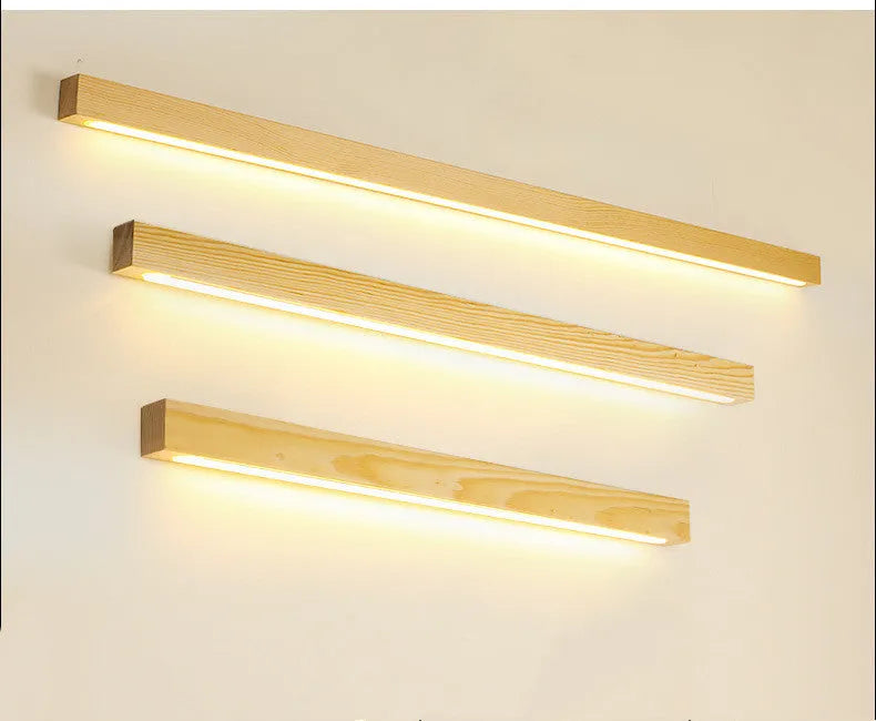 Modern walnut-coloured log strip wall lamp in three sizes on a white wall.