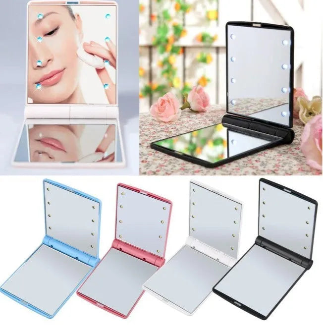 Folding LED pocket cosmetic mirror in black, blue, pink, or white with protective lid and compact plastic casing for handbag or travel use.