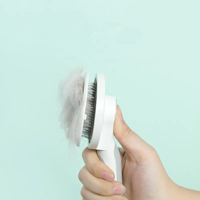 Round handle pet pass-through comb with stainless steel needles and self-cleaning button in pink colour