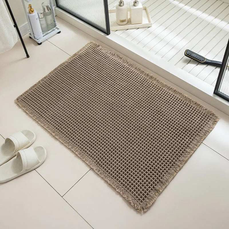 Square checkered pattern non-slip bathroom carpet on tiled floor in beige colour.