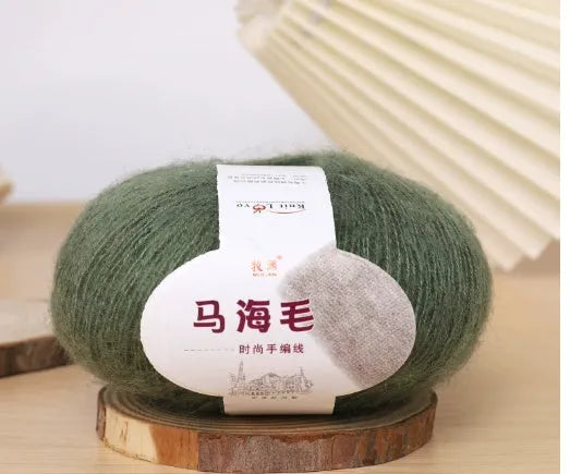 A ball of mohair yarn in a selected colour next to a hand-woven scarf example, showcasing the DIY kit.