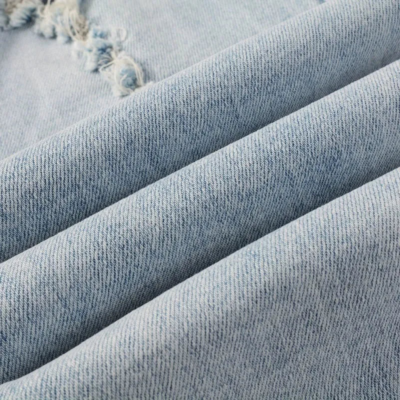 Light blue slim fit men's jeans with patch details, holes, and enzyme-washed finish