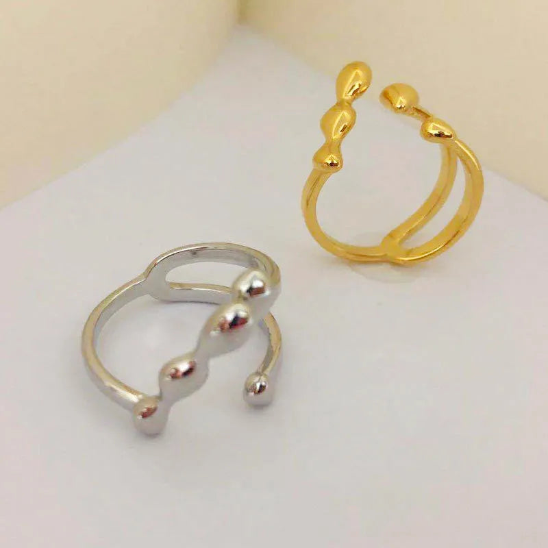 Gold tone brass ring with open circle design and central sphere on a person's finger.